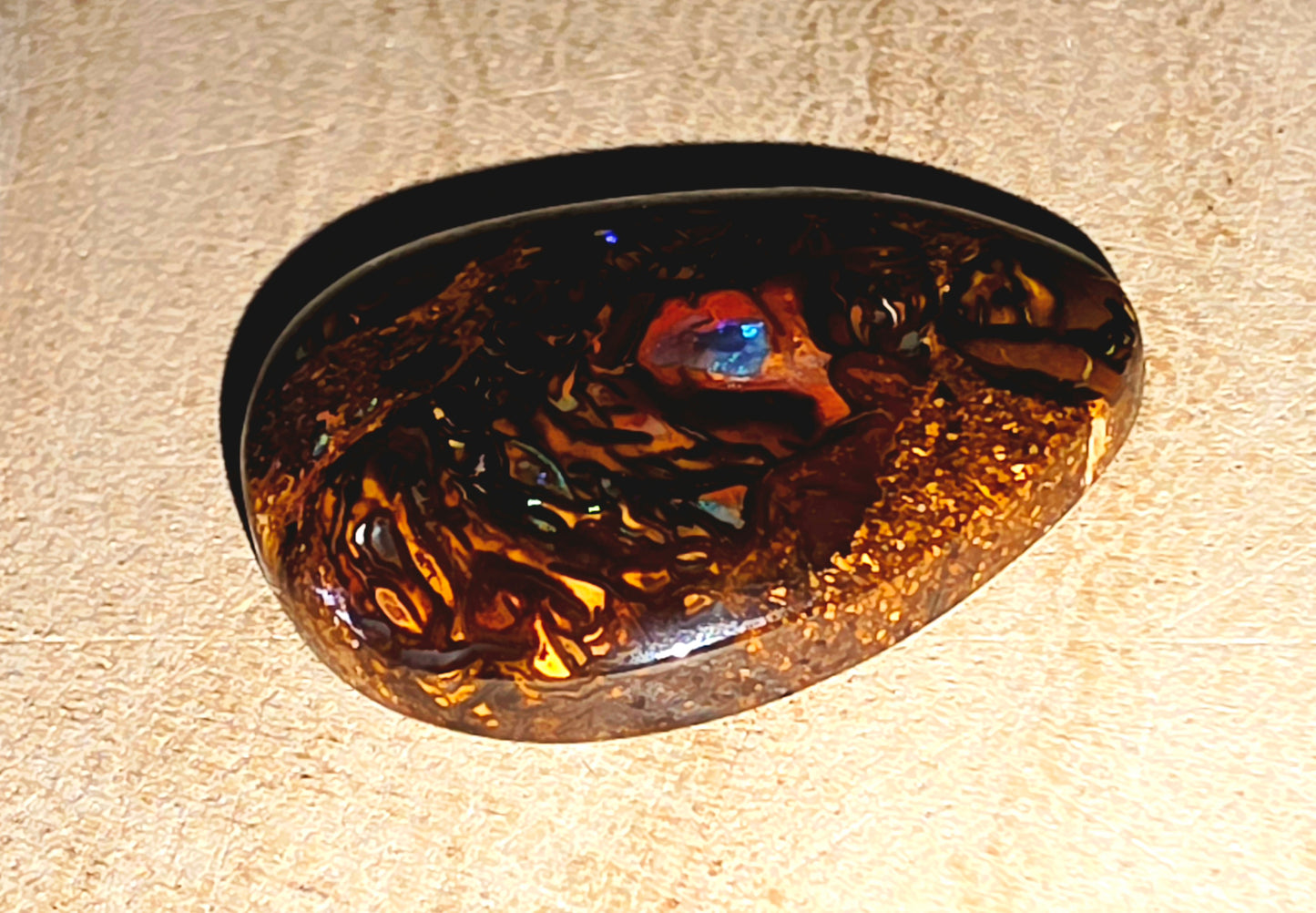 Tortoiseshell-patterned boulder opal on a beige background