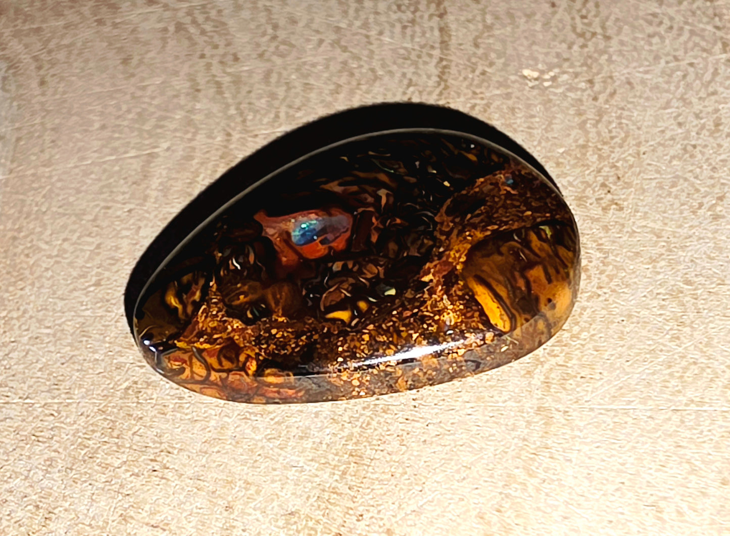 Decorative opal with embedded colourful pebbles on a beige surface