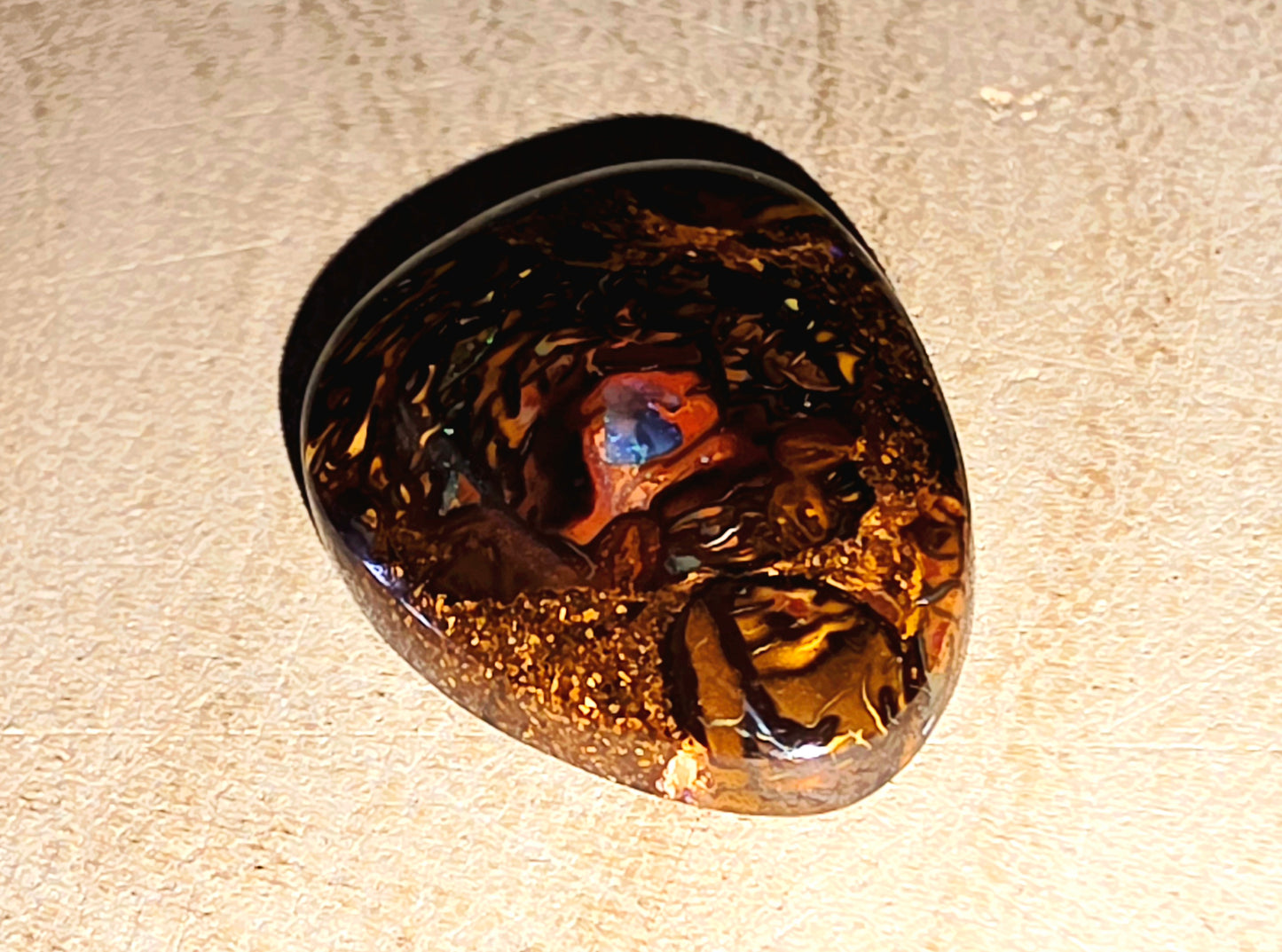 Brown boulder opal with a blue centre on a beige surface