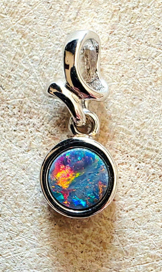Silver pendant with a colourful opal gemstone on a beige background