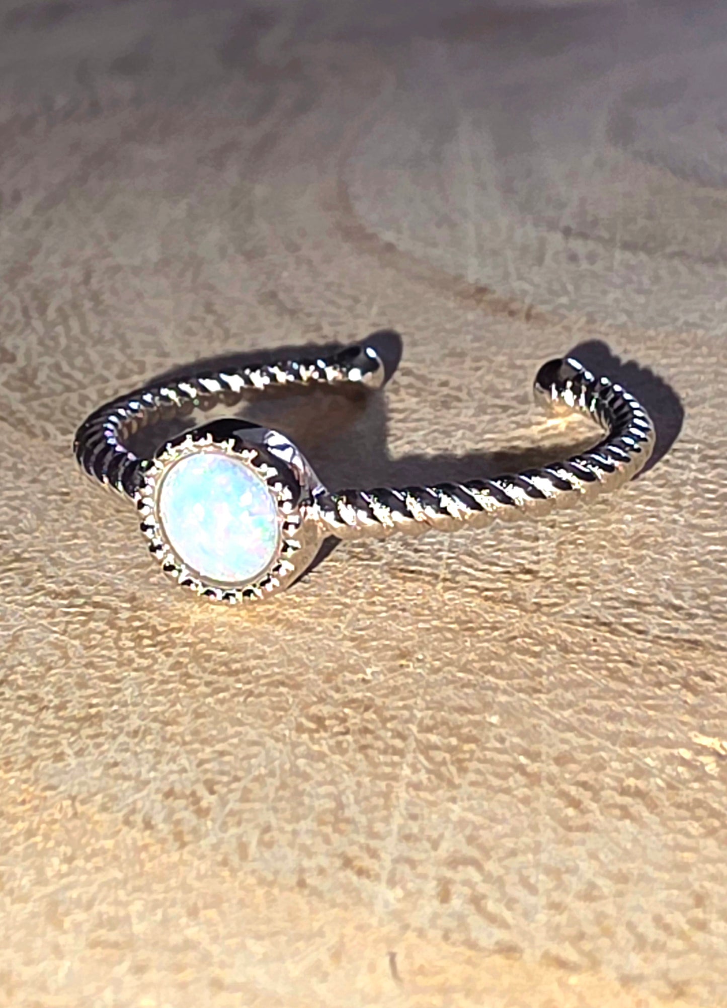 Silver ring with a central gemstone on a textured beige surface