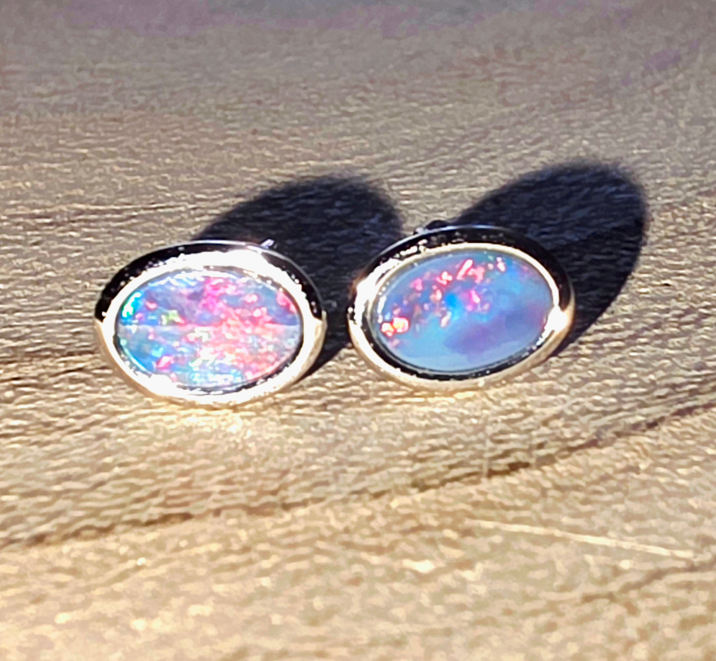 Pair of opal stud earrings on a textured surface