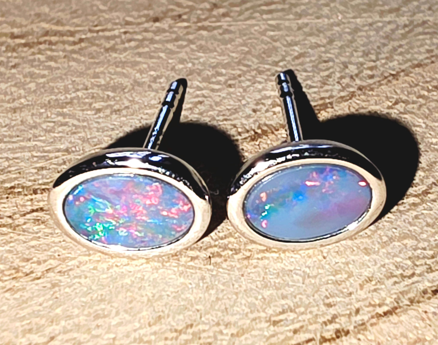 Pair of opal stud earrings on a wooden surface