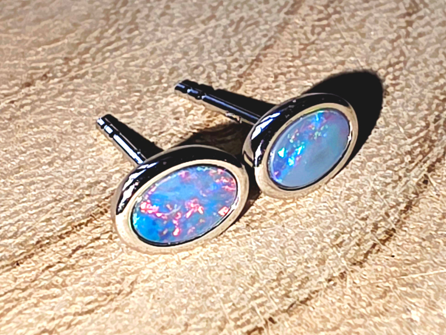 Opal earrings on a textured beige surface