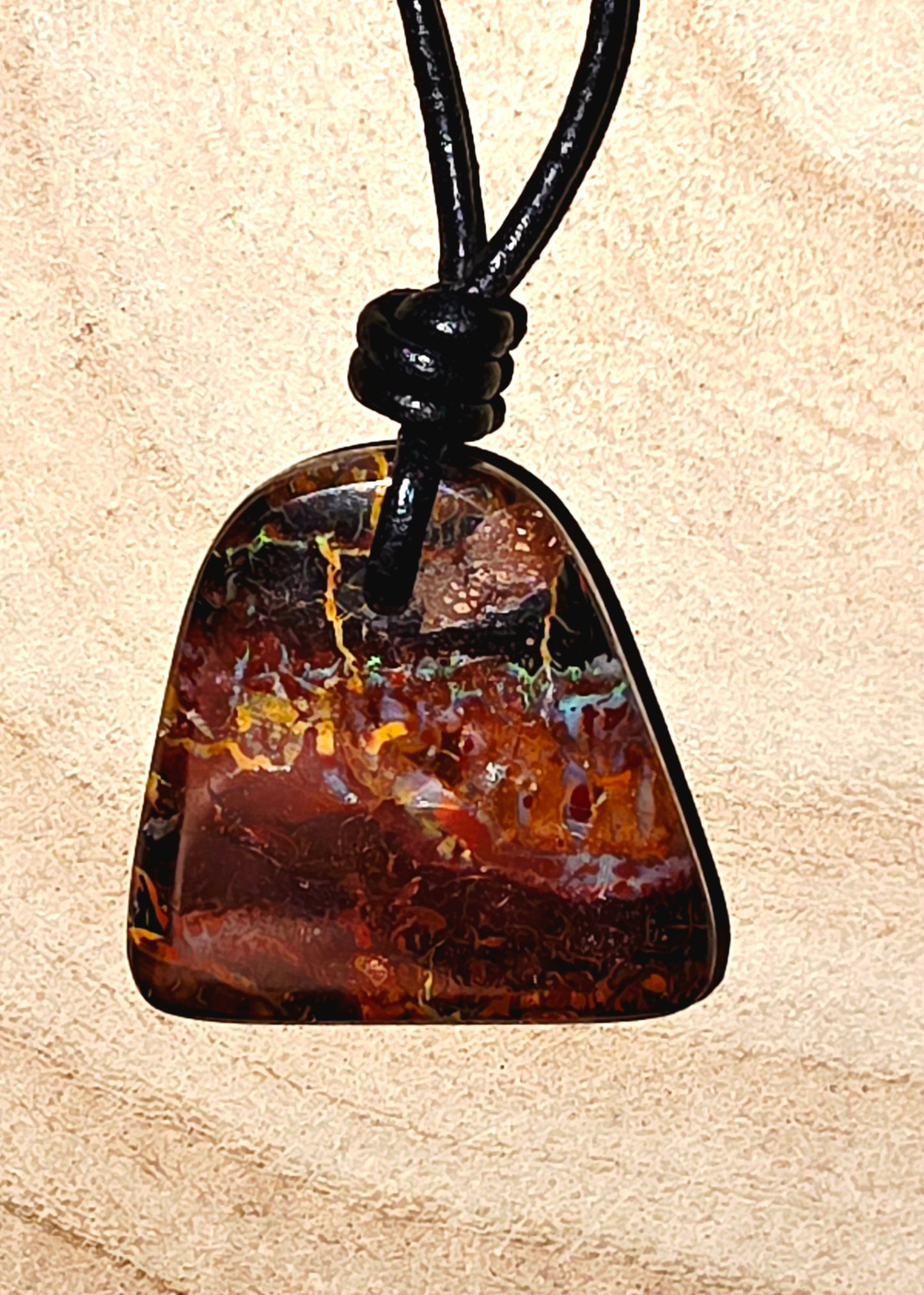Brown stone pendant on a black cord against a beige background