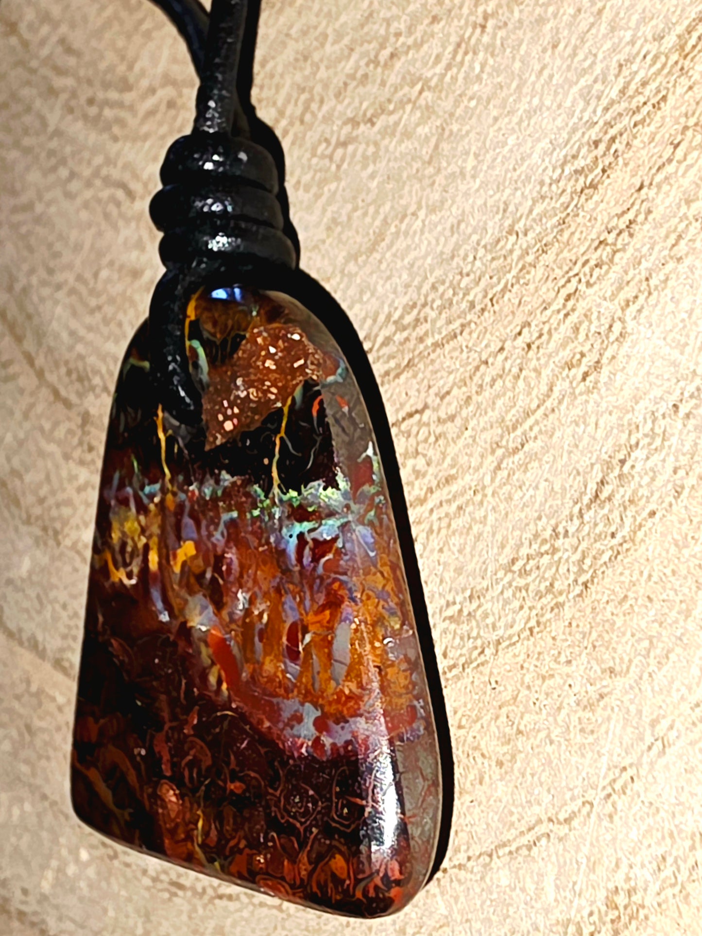 Pendant with a textured, multicoloured stone on a beige background