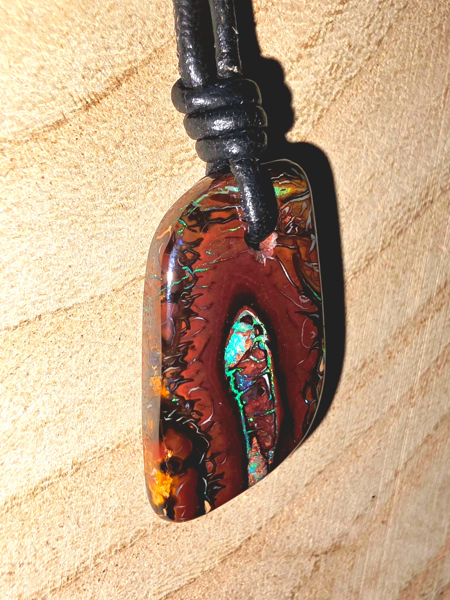 Multicoloured pendant on a leather cord against a beige background