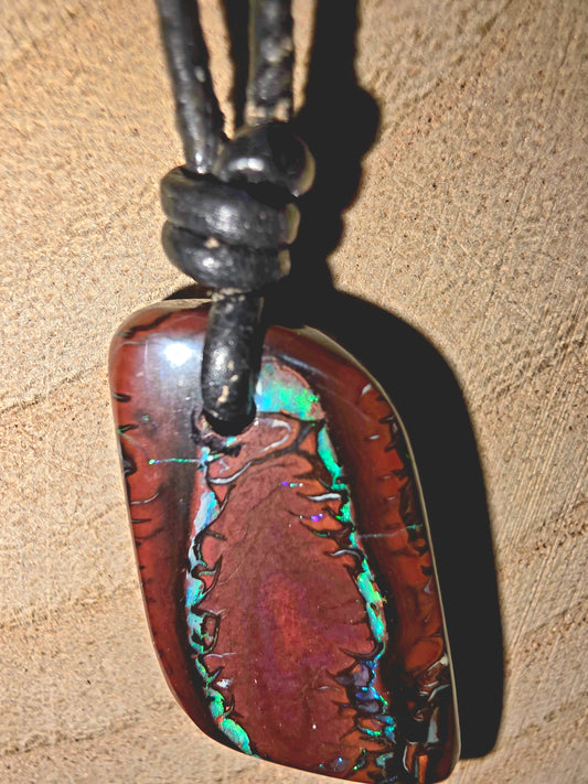 Multicolored stone pendant on a leather cord against a beige background