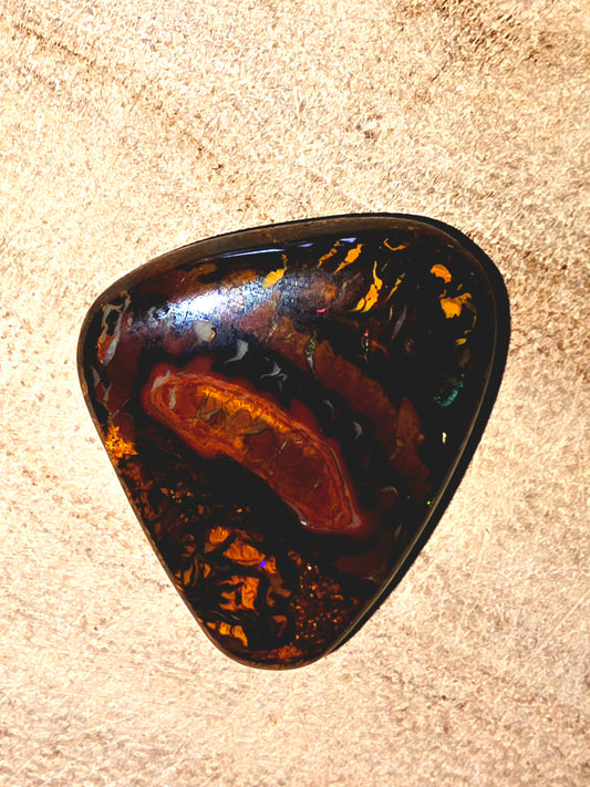 Triangular opal stone on a beige surface