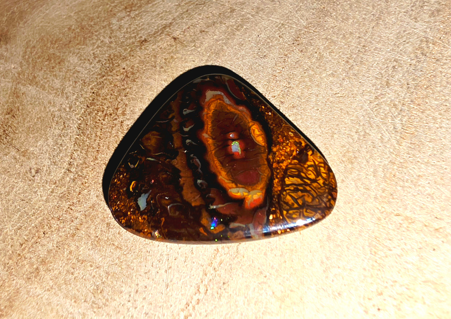 Triangular opal stone on a beige surface
