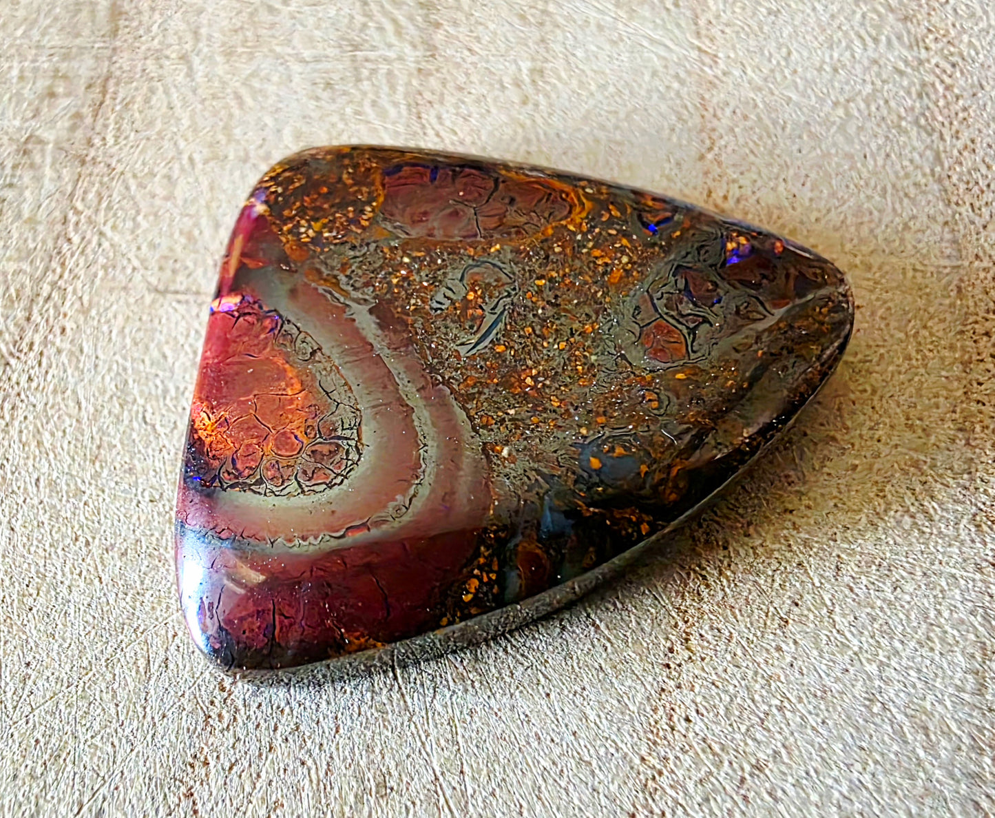 Multicoloured opal stone on a textured beige surface