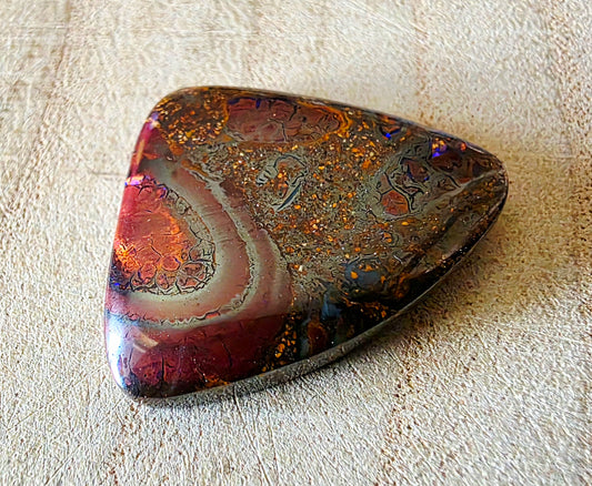 Multicoloured opal stone on a textured beige surface