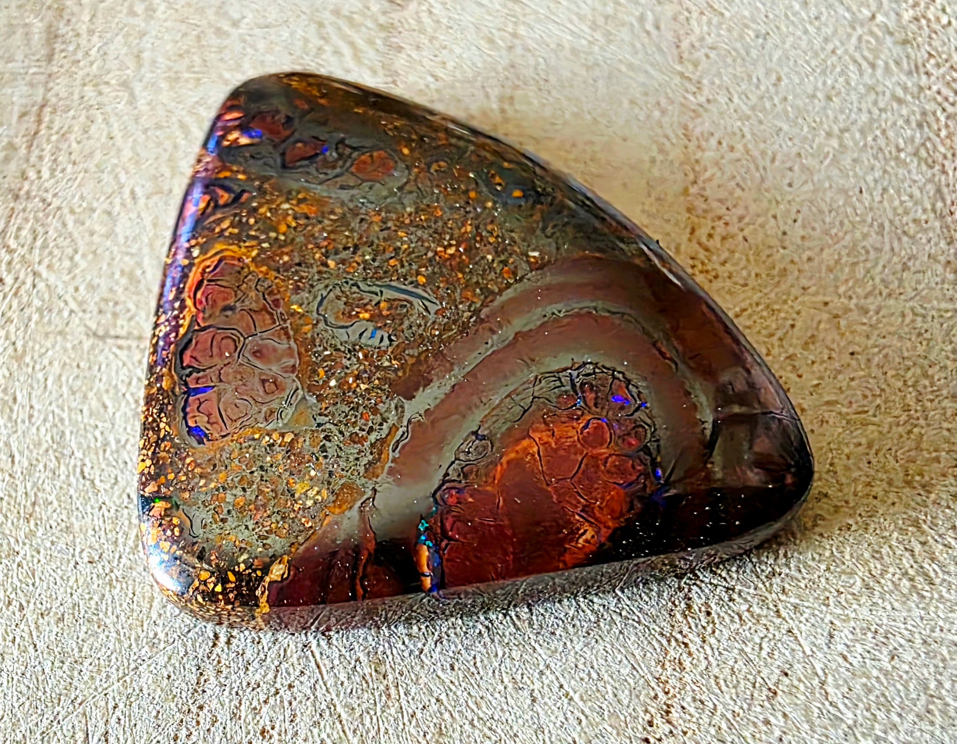 Polished piece of opal stone on a textured surface