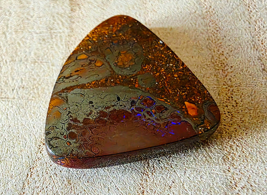Polished piece of opal material on a textured surface