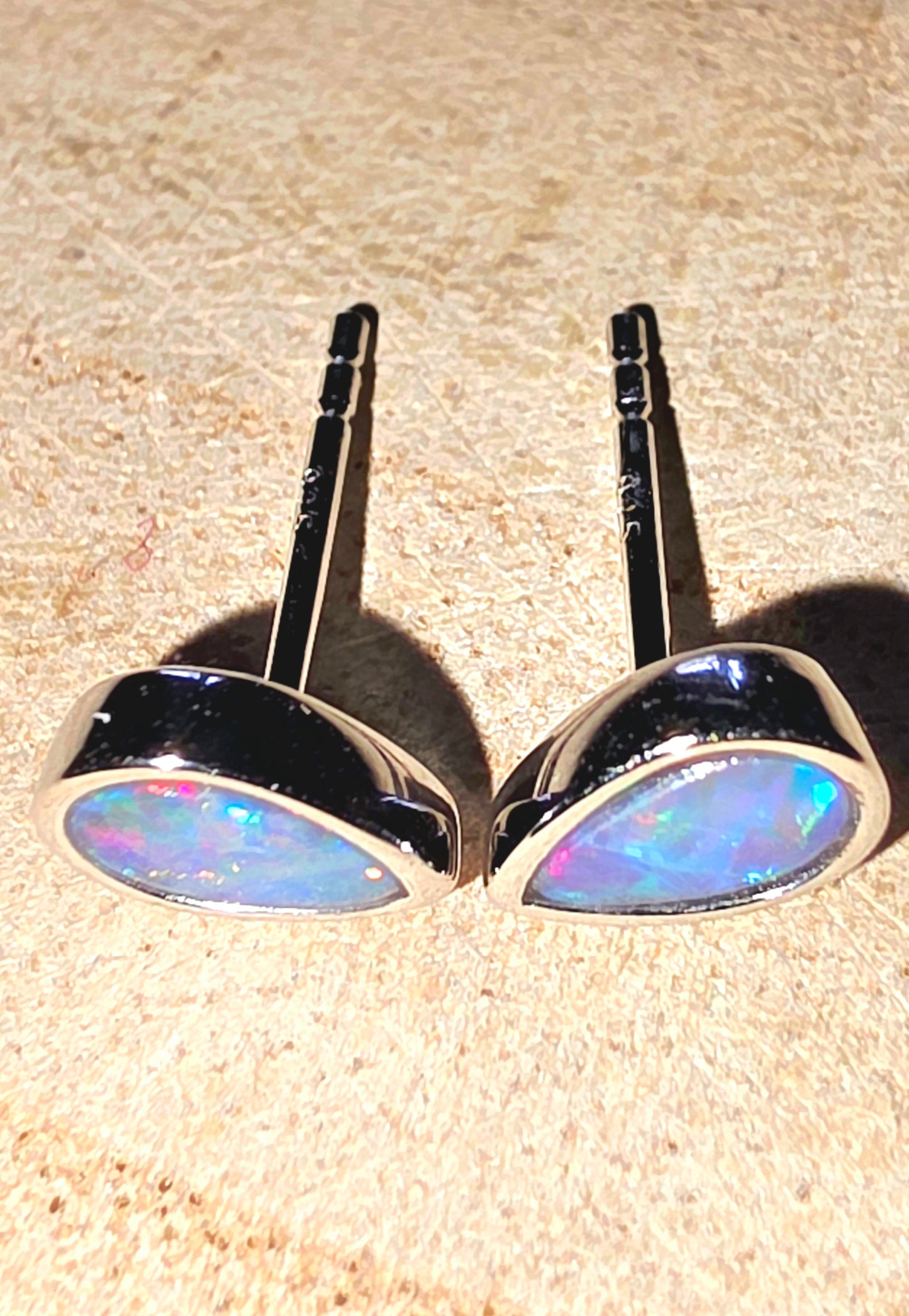 Pair of opal earrings on a beige surface