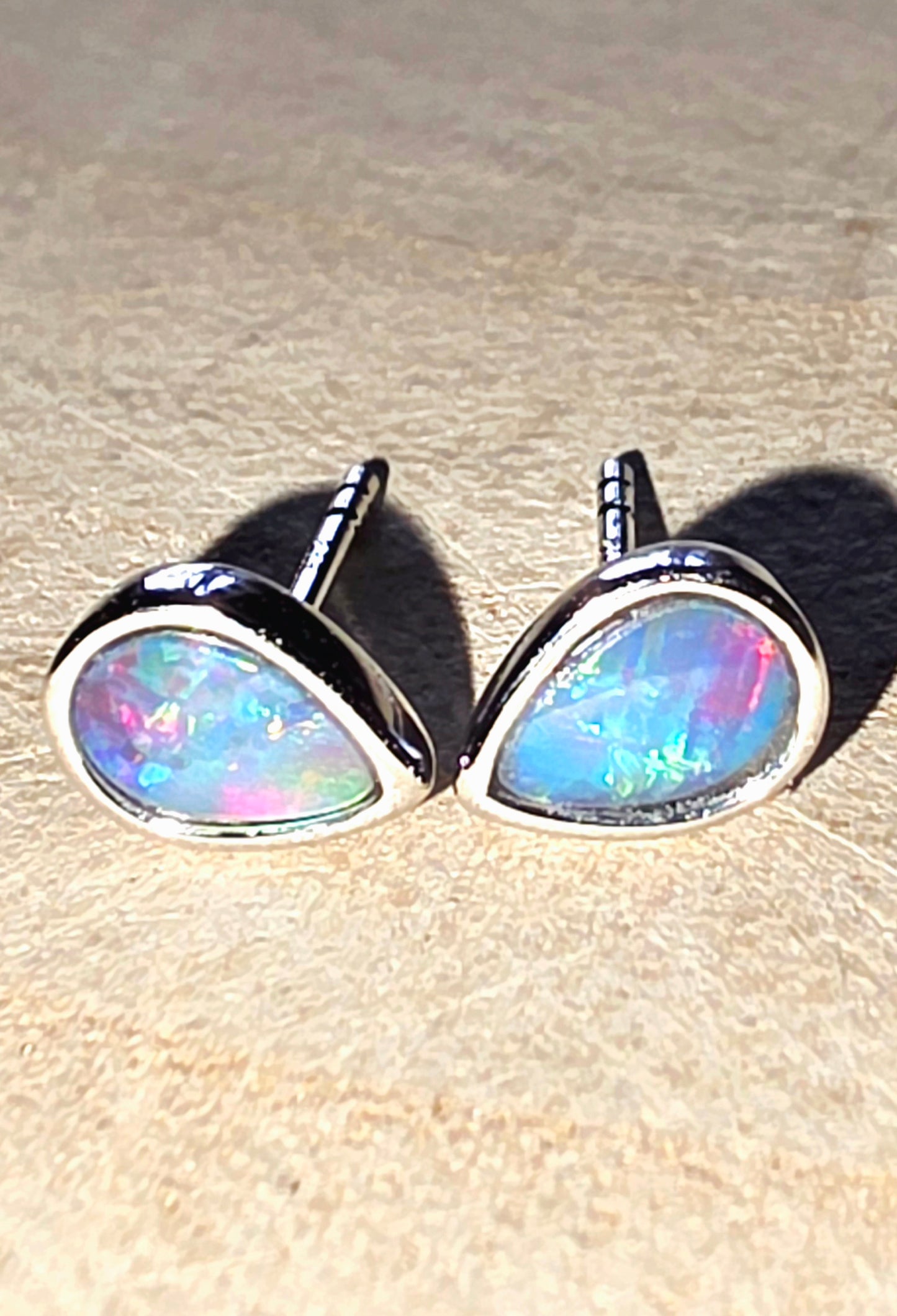 Opal stud earrings on a beige surface