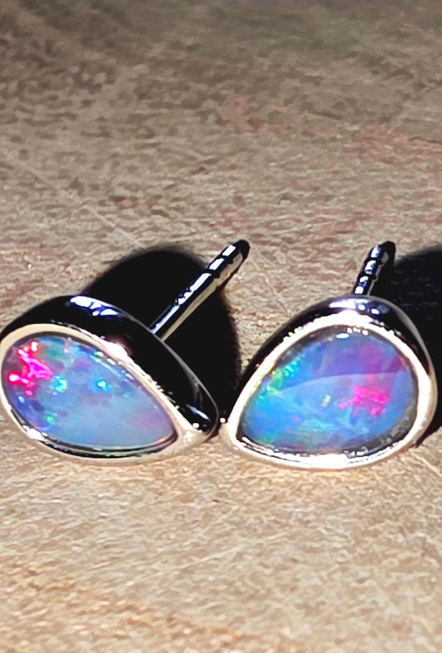 Opal stud earrings on a textured surface