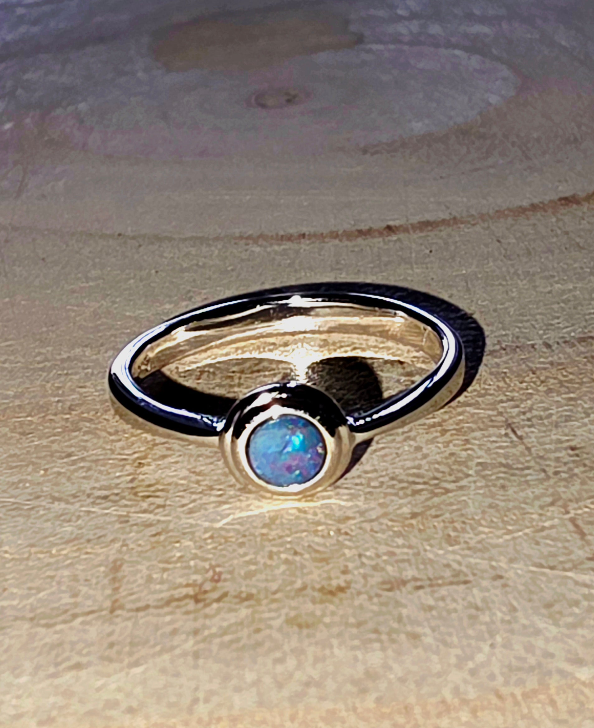 Silver ring with a central gemstone on a wood surface