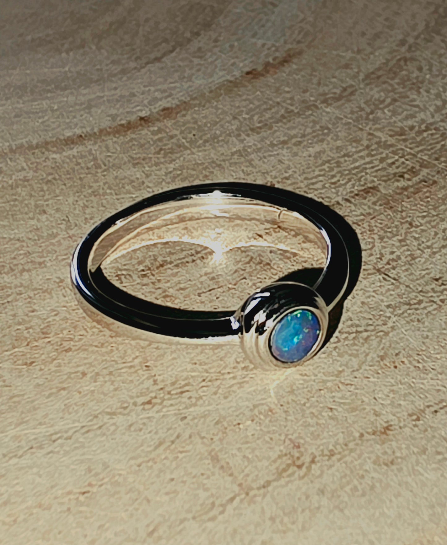 Silver ring with a central gemstone on a wood surface
