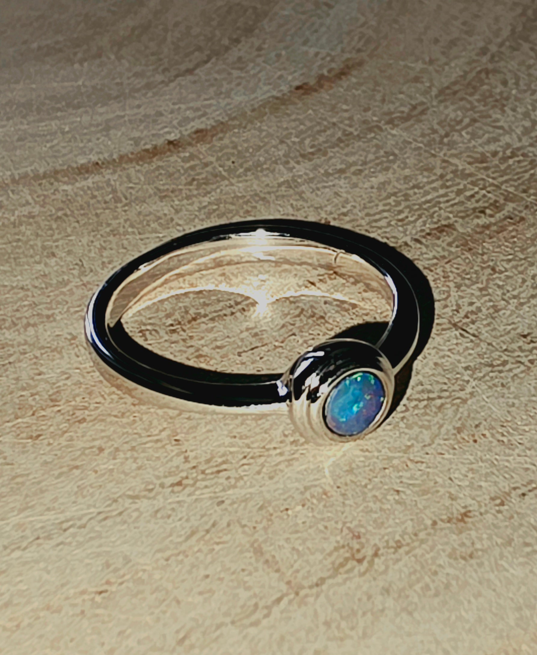 Silver ring with a central gemstone on a wood surface
