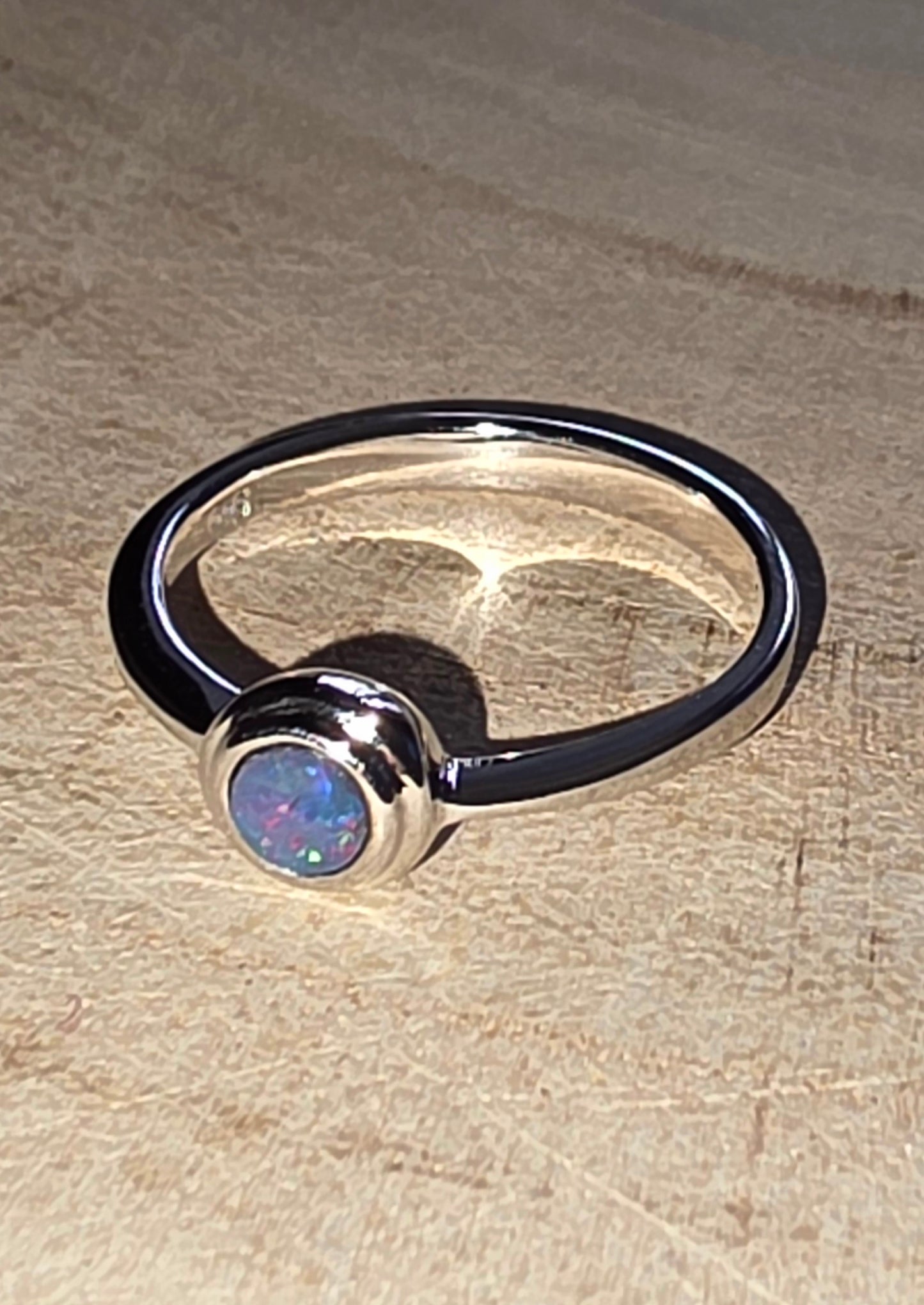 Silver ring with a central gemstone on a wood surface