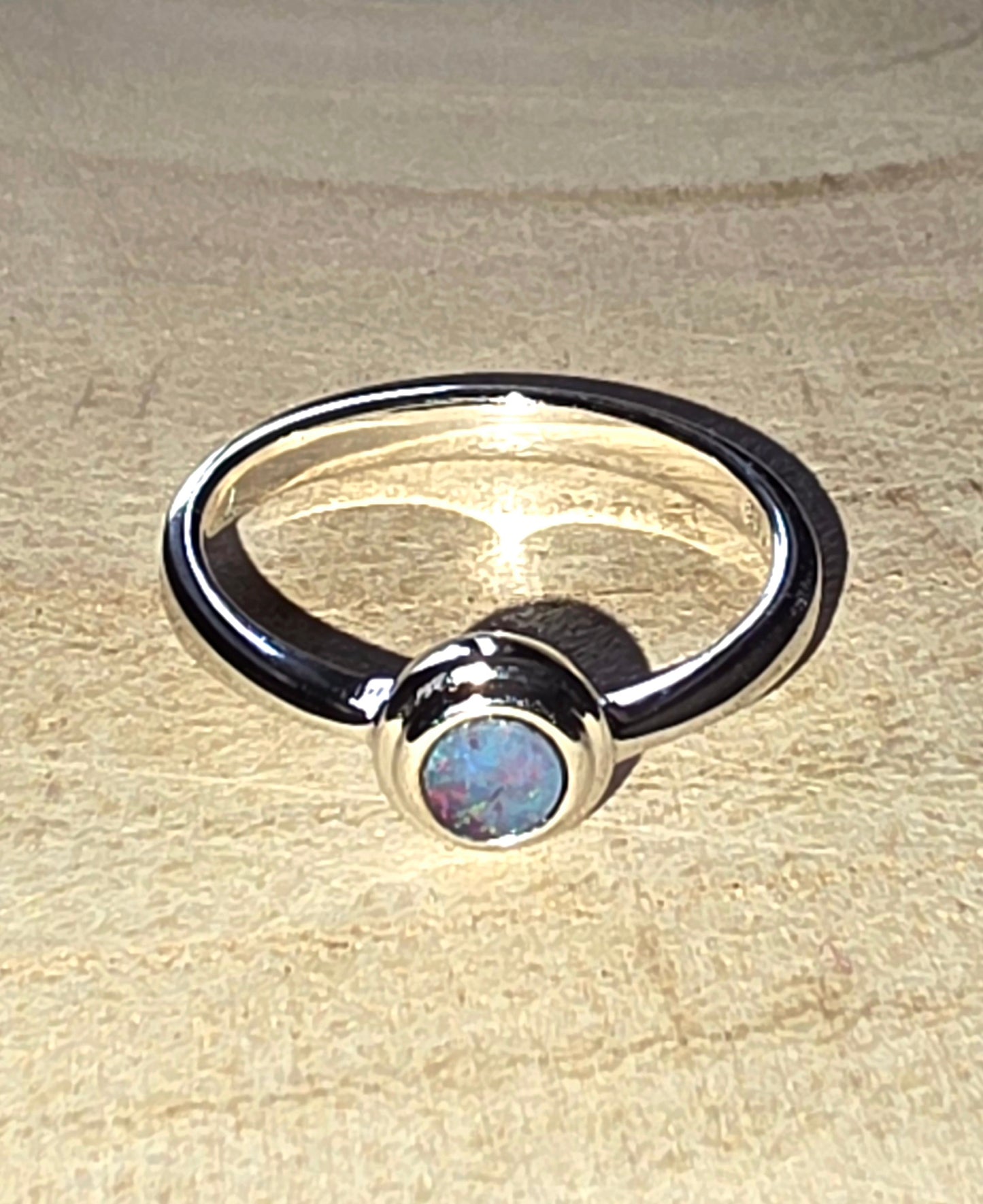 Silver ring with a central gemstone on a beige surface
