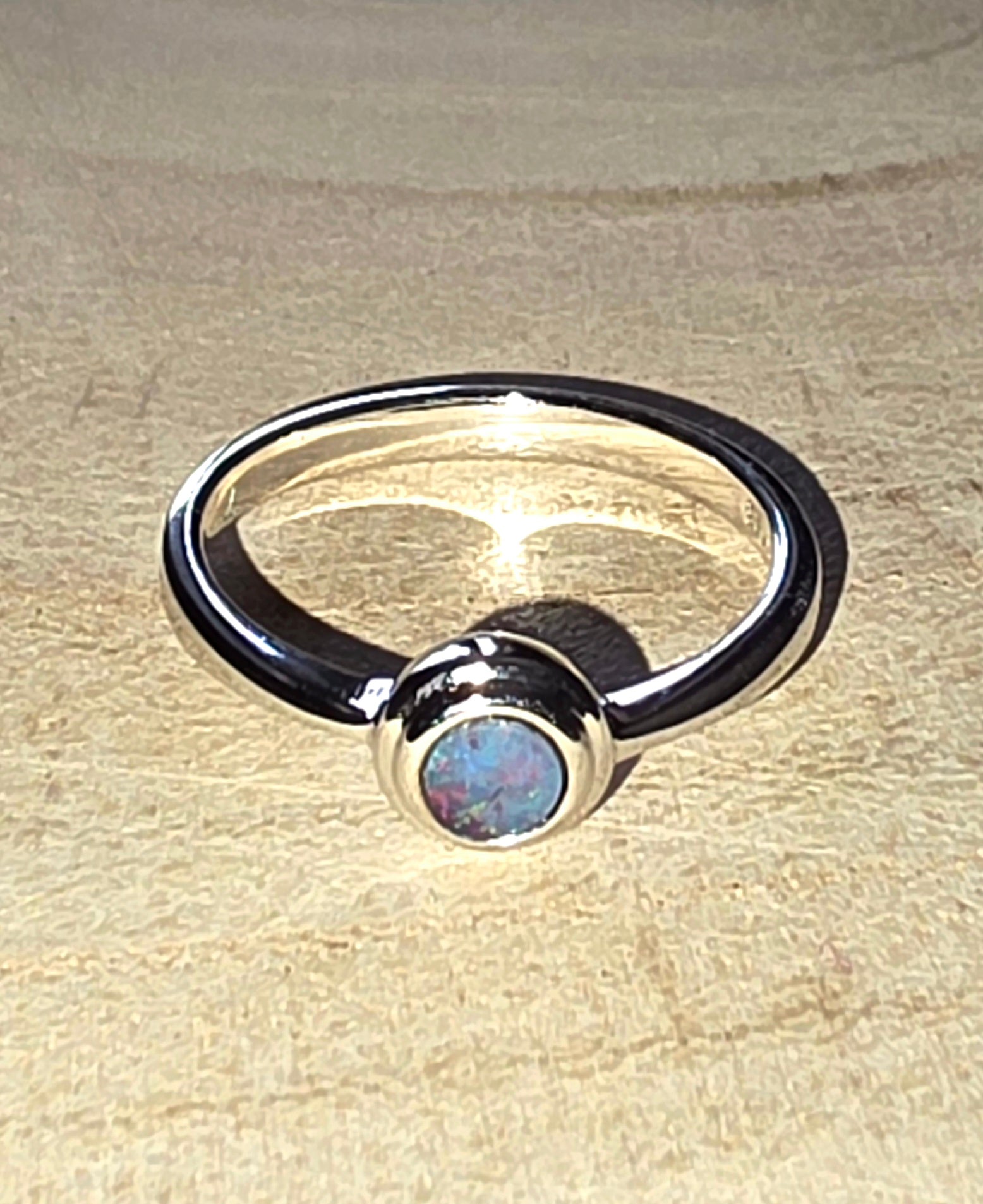 Silver ring with a central gemstone on a beige surface