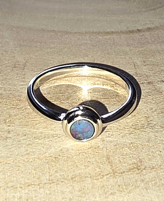 Silver ring with a central gemstone on a beige surface