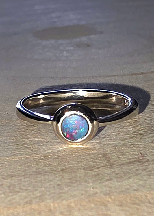 Silver opal ring with a central gemstone on a beige surface