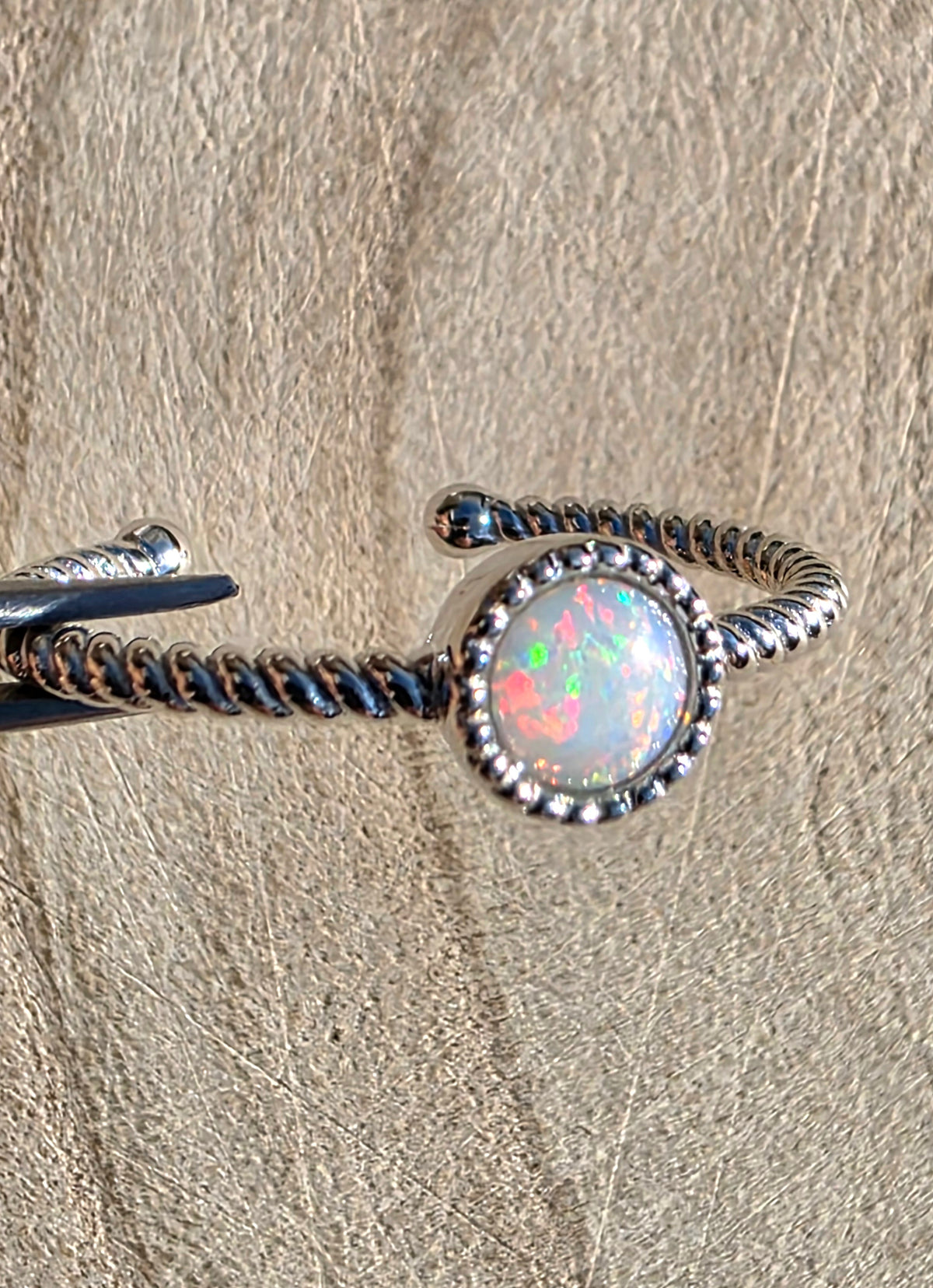 A white opal ring on a silver twisted role style setting