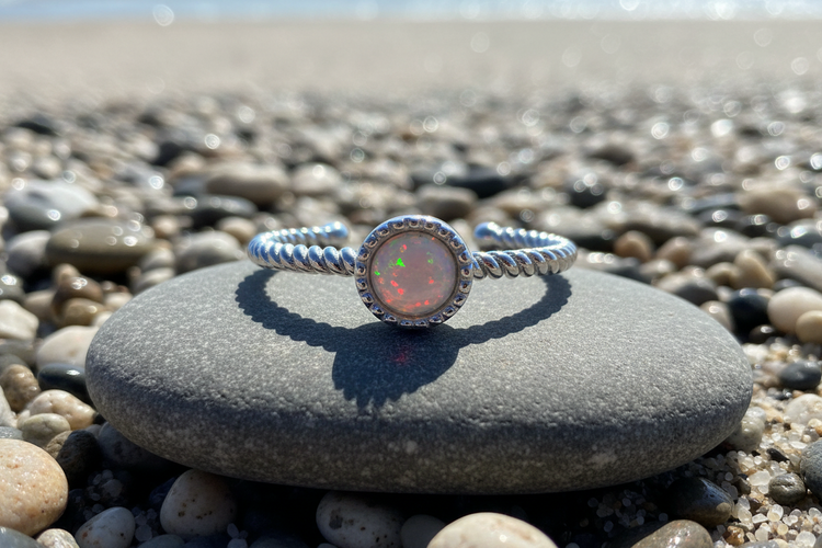 A crystal opal ring on a beach stone