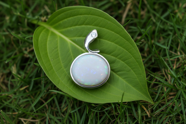 A white opal pendant on a leaf